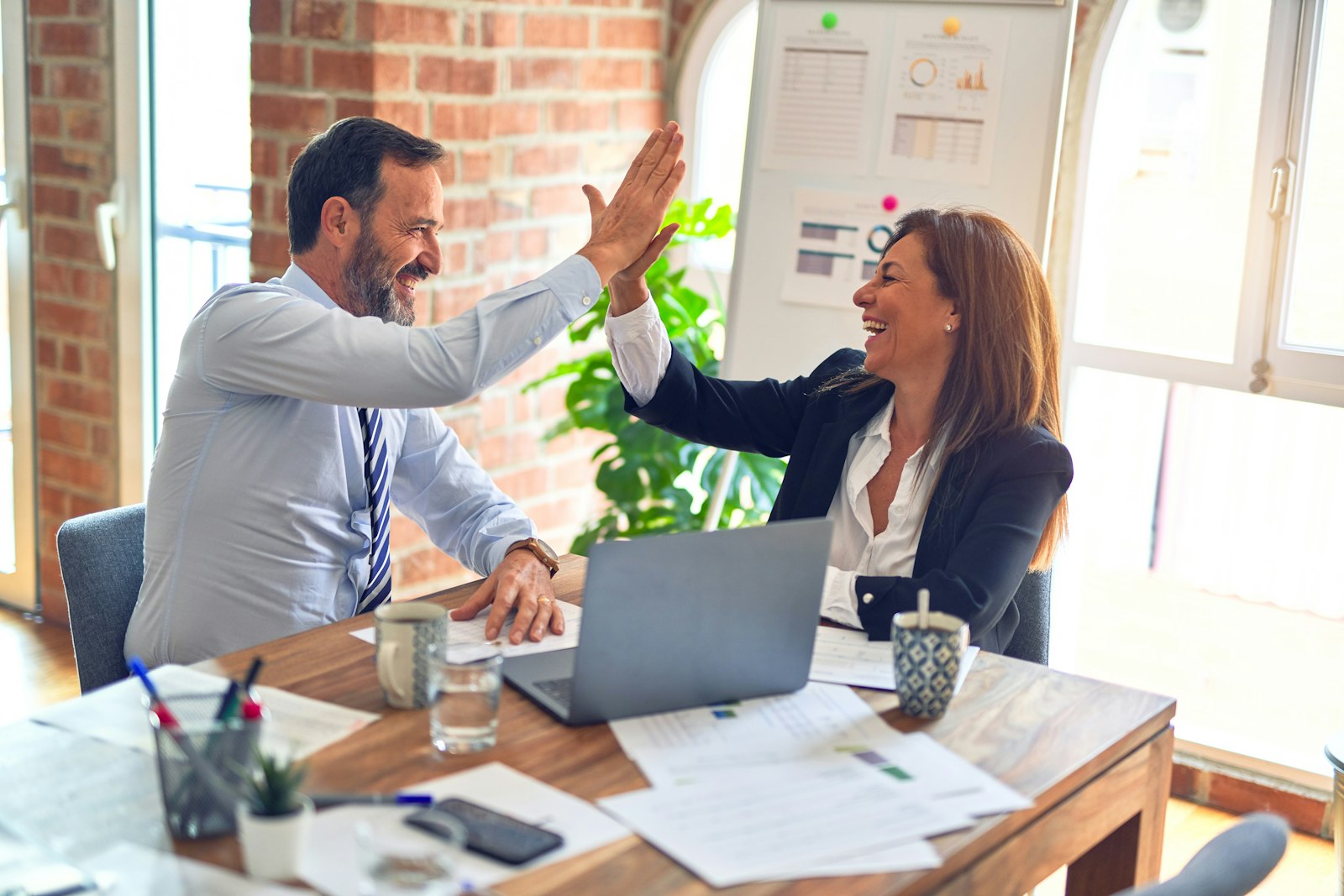Two colleagues celebrating a successful meeting with a high-five. The kind of partnership that starts a ReFiles pilot